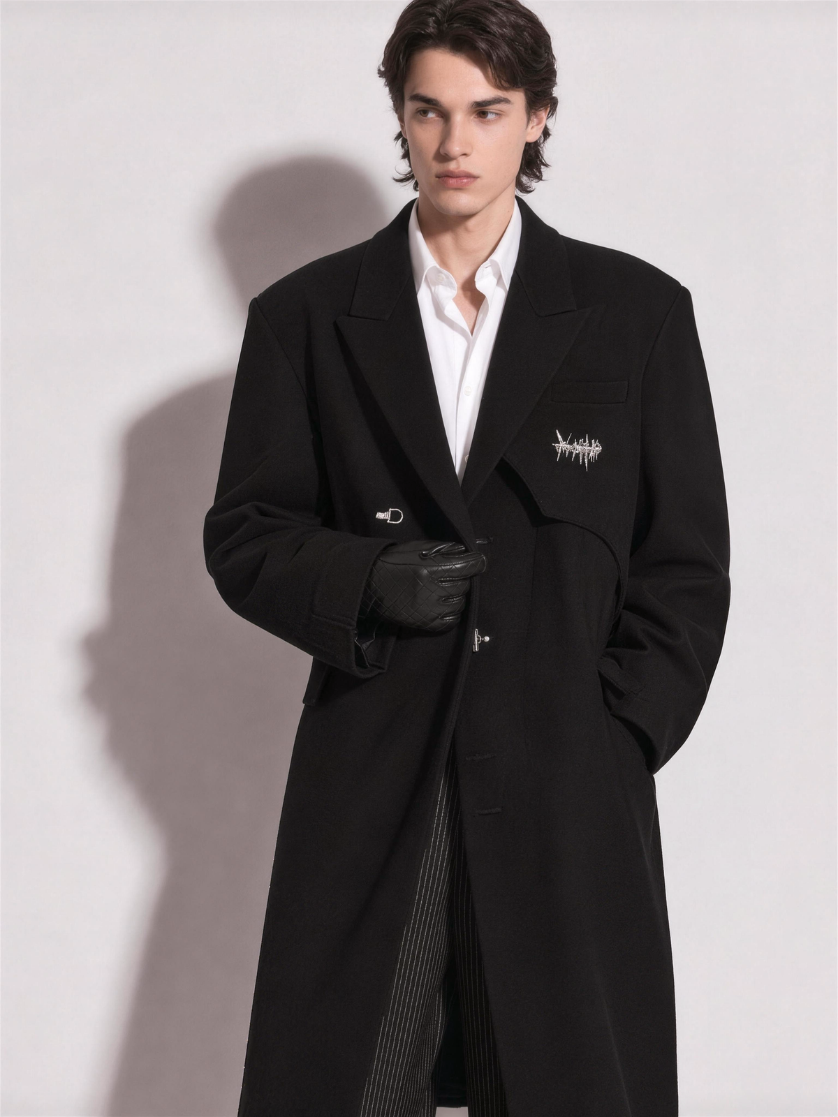 Model in the oversized overcoat with gloved hand at the lapel