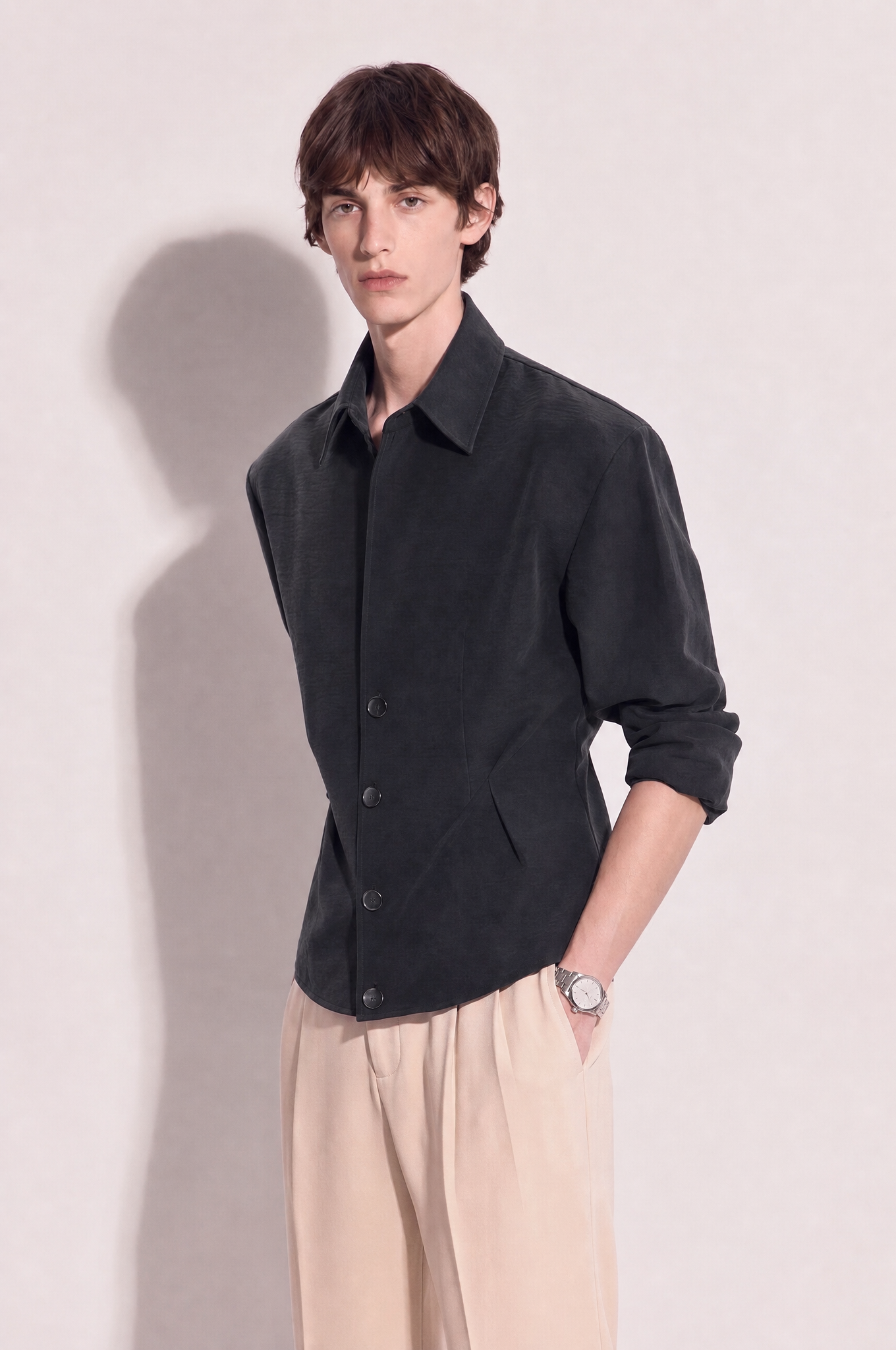 Structured button-up shirt with cinch side detail in dark charcoal, three-quarter view showing waist darts and structured shoulder