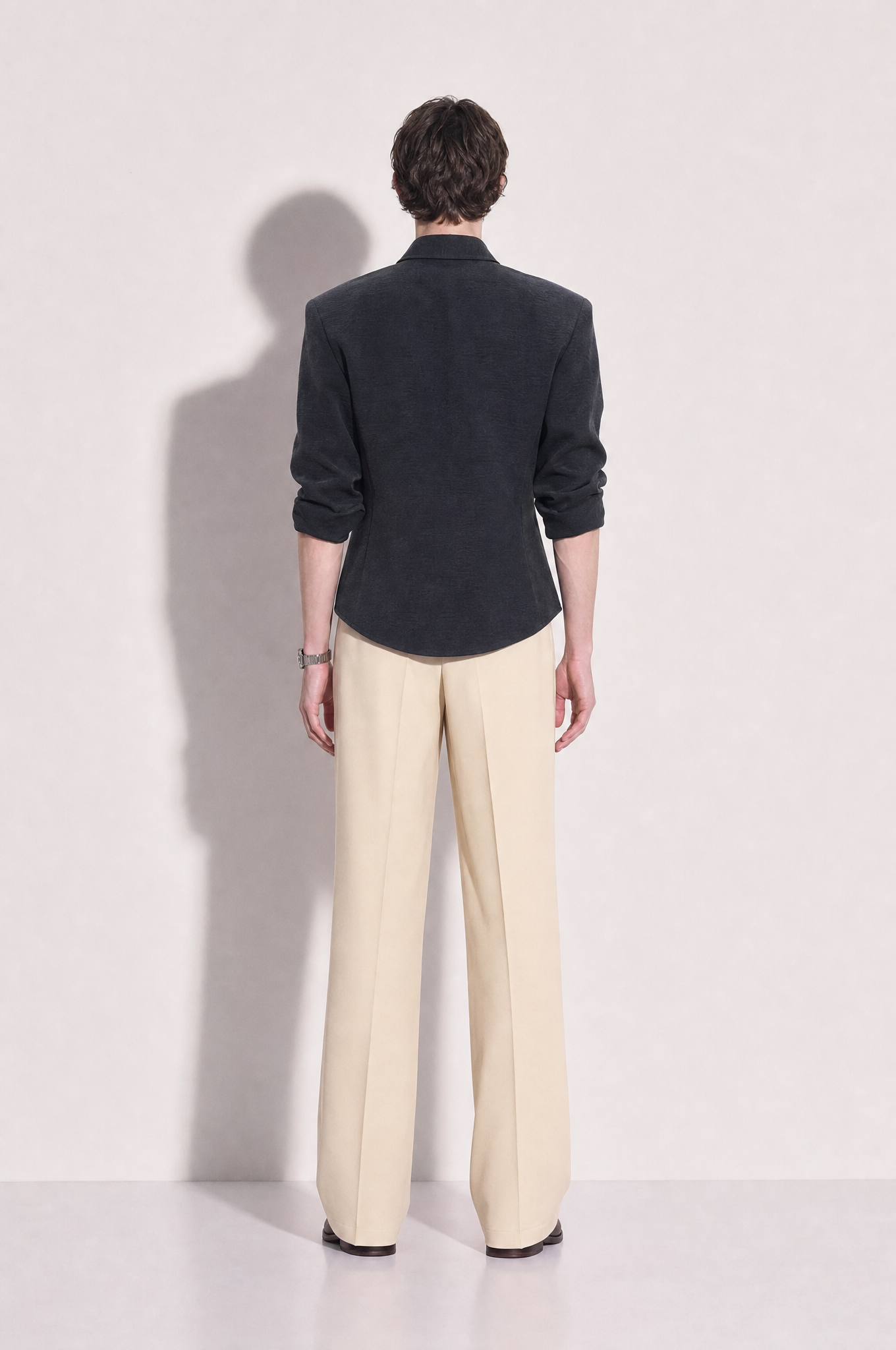 Structured button-up shirt with cinch side detail in dark charcoal, rear full body view showing structured shoulders and curved hem
