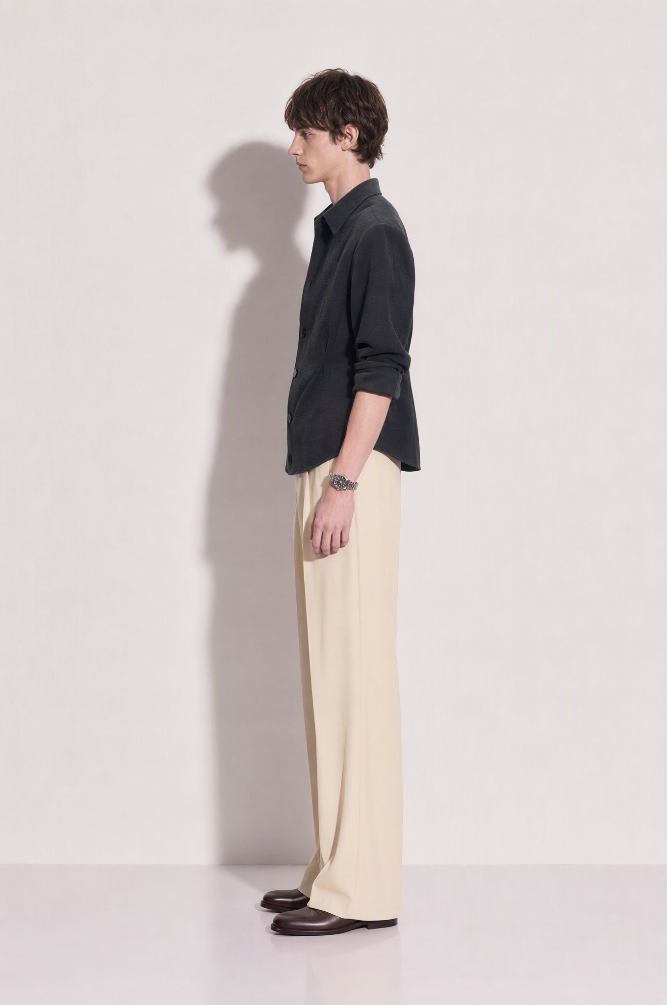Structured button-up shirt with cinch side detail in dark charcoal, side profile full body view